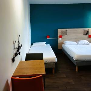 Zimmer mit 2 Betten, einem Tisch und einer blauen Wand in der Unterkunft hotelF1 Lyon Bourgoin-Jallieu in LʼIsle-dʼAbeau