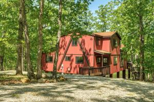 uma casa vermelha no meio da floresta em 1730 Tarnhouse Lakefront Cottage by Sarah Bernard Vacation Rentals em Innsbrook