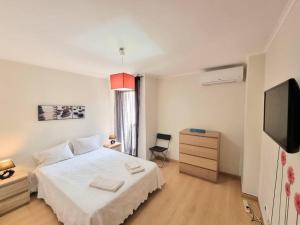 una camera con letto bianco e TV a schermo piatto di Apartamento Sol e Praia - T2 na Praia de Monte Gordo a Monte Gordo