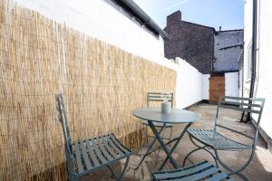 un patio con 2 sillas, una mesa y una pared en Air Host and Stay - Earp House 3 bedroom, sleeps 7, mins from train, en Liverpool