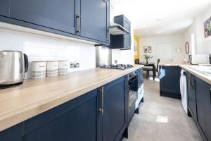 a kitchen with blue cabinets and a wooden counter top at Air Host and Stay - Earp House 3 bedroom, sleeps 7, mins from train in Liverpool