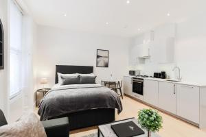 a white bedroom with a bed and a kitchen at Olympic Park Apartments in London