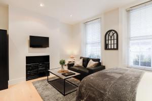 ein Wohnzimmer mit einem Bett, einem Sofa und einem TV in der Unterkunft Olympic Park Apartments in London