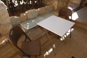 einen weißen Tisch, zwei Stühle und eine Bank in der Unterkunft Giardino del Mare in Bordighera