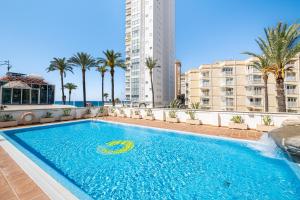 a swimming pool with palm trees and a building at Acintur Apartment Levante Beach-Old Town in Benidorm