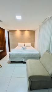 ジョアンペソアにあるHotel Pousada Kairos Manairaのベッド2台とソファが備わるホテルルームです。
