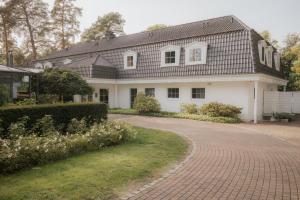 ein weißes Haus mit einem schwarzen Dach und einer steinernen Einfahrt in der Unterkunft nook x Seepalais Boutique Hotel in Bad Saarow