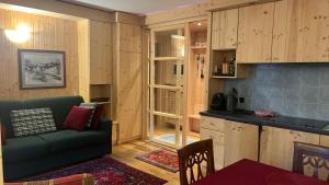 a living room with a green couch and a kitchen at MONOLOCALE LA BORMINA in Bormio
