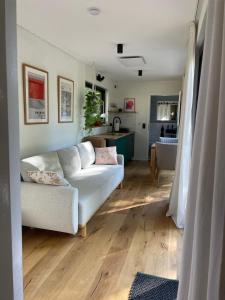 Cozy Cabins I Tiny House Seecontainer في بوكسفيس هاننكلي: غرفة معيشة مع أريكة بيضاء ومطبخ