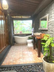 uma casa de banho com uma banheira, um WC e uma janela. em JANE’S HOUSE & SPA BEDUGUL BALI em Patjung