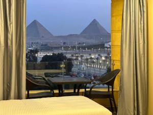 開羅的住宿－Asia Grand Museum & Pyramids view，阳台享有金字塔的景致,配有桌椅。