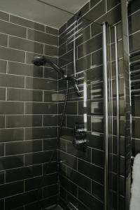 a shower in a black tiled bathroom at Retreat on the Green in Holt