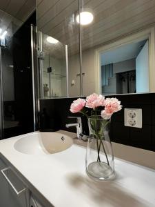 un vase avec des fleurs roses assises sur un lavabo dans la salle de bains dans l'établissement Penthouse Loft - Near the Airport, à Vantaa