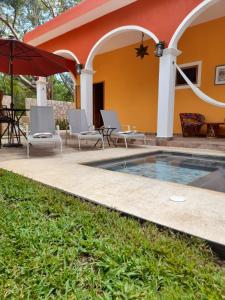 a swimming pool with chairs and an umbrella next to a house at VILLA UNAHANA in Valladolid