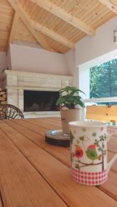 a coffee cup sitting on a wooden table with a fireplace at Vila Snjeguljica Blidinje 200 m od ski staze in Risovac