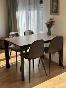 una mesa de comedor con sillas y un jarrón de flores en OLIMPIC Apartament Klimatyzacja Garaż Winda Suwałki en Suwałki