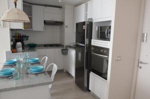 una cocina con armarios blancos y una mesa con platos azules. en Valemar, en La Serena