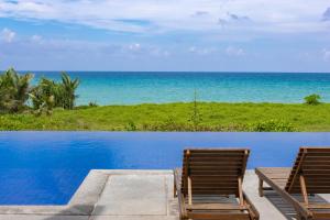 2 sillas sentadas junto a una piscina con el océano en 8卧沙滩别墅 3女佣 每日清洁 靠近机场 私人泳池 免费用车 健身房, en Phuket