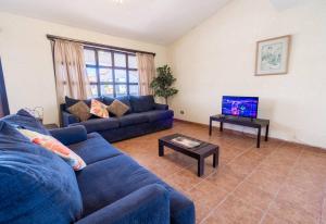 ein Wohnzimmer mit einem blauen Sofa und einem TV in der Unterkunft La Hacienda San Felipe Condo 18 in San Felipe