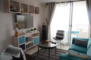 sala de estar con sofá azul y TV en Valemar, en La Serena