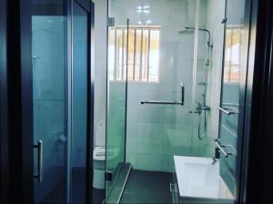 a bathroom with a glass shower and a sink at Luxurythemain in Ibadan