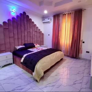 um quarto com uma cama grande e uma grande cabeceira. em Luxurythemain em Ibadan