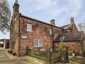 an old brick building with a fence in front of it at The Granary in Biddulph