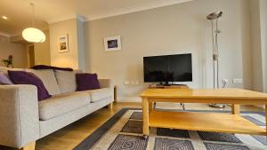 a living room with a couch and a tv at Castle Pond House in Pembroke