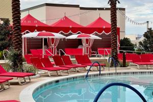 a pool at a resort with red chairs and umbrellas at Elegant Stay at Resorts World Strip Las Vegas in Las Vegas