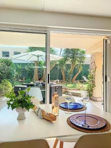a dining room with a table with chairs and a table at Superbe appartement avec Jardin in Villeneuve-Loubet