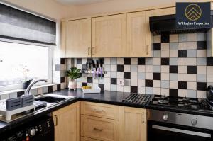 uma cozinha com armários de madeira e azulejos pretos e brancos em Exclusive Two Bedroom House by AV Hughes Properties Short Lets & Serviced Accommodation Northampton For Families & Business em Kingsthorpe