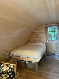 Cama en habitación de madera con ventana en The Nest cabin, en Ipswich