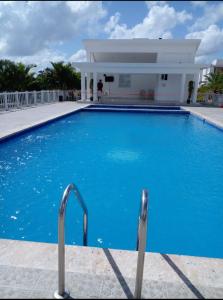 a swimming pool with blue water in front of a building at Hermoso residencial con piscina licey al medio in Licey al Medio