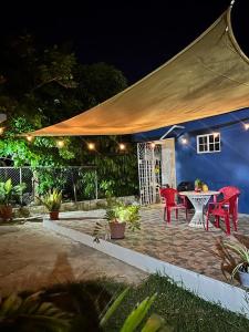 eine Terrasse mit roten Stühlen und einem Tisch mit einem Zelt in der Unterkunft Something Blue in Savanna-la-Mar
