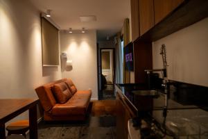 una sala de estar con una silla marrón y una mesa en Caravaggio Container Inn (7 min d Caminho d Pedras), en Farroupilha