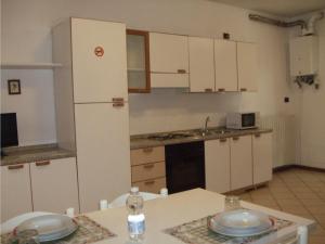 La cuisine est équipée de placards blancs et d'un réfrigérateur blanc. dans l'établissement Foresteria Casa Dante, à Leno