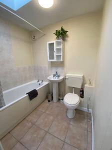 a bathroom with a tub and a toilet and a sink at Unique Bungalow Grangetown in Cardiff