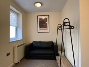 a black leather couch in a room with a window at Unique Bungalow Grangetown in Cardiff