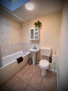 a bathroom with a toilet and a tub and a sink at Unique Bungalow Grangetown in Cardiff