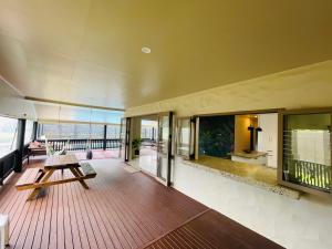 Großes Zimmer mit einer Holzterrasse mit einem Tisch. in der Unterkunft Villa Honey Rose - Rarotonga in Arorangi