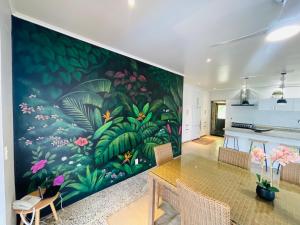 ein Esszimmer mit einem großen Wandbild von Pflanzen in der Unterkunft Villa Honey Rose - Rarotonga in Arorangi
