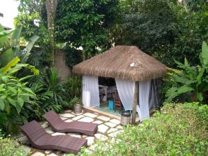 a garden with two chairs and a hut at Suítes Km18praia in Barra do Una