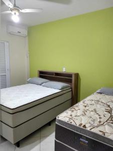 a bedroom with two beds and a green wall at Casa espaçosa 3 dorms no Centro de Bombinhas in Bombinhas