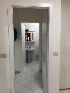Baño blanco con lavabo y espejo en La casa di Dafne en Messina