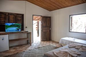 Schlafzimmer mit einem Bett, einem TV und einer Tür in der Unterkunft Orla Atins in Atins