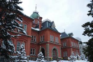 un gran edificio de ladrillo rojo con nieve. en Carid Shiraishi In front of the station - Vacation STAY 15498, en Sapporo