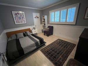 a bedroom with a bed and a chair and a window at Chic Venice Beach Bungalow Steps from the Canals & Beach in Los Angeles