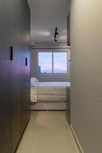 a bedroom with a bed and a window at Apartamento moderno, com home office e garagem. in Goiânia