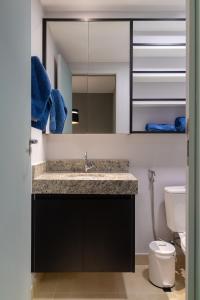 a bathroom with a sink and a mirror and a toilet at Apartamento moderno, com home office e garagem. in Goiânia