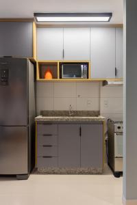 a kitchen with a sink and a microwave at Apartamento moderno, com home office e garagem. in Goiânia